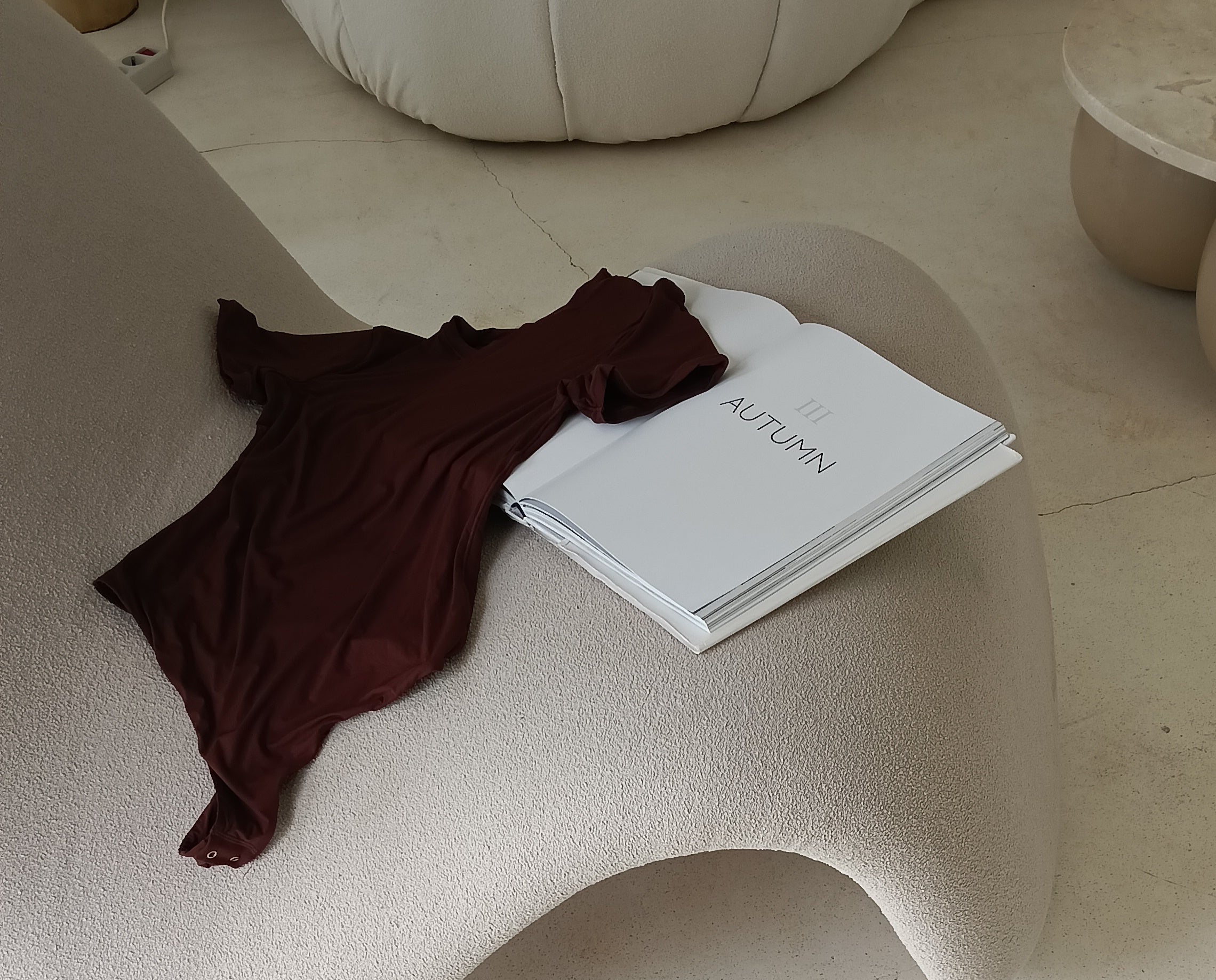 Book titled 'Autumn' on a textured surface with a brown garment draped over it.