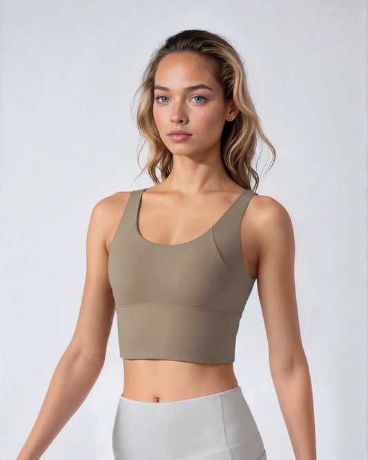 Woman wearing a beige sports bra and gray leggings against a white background